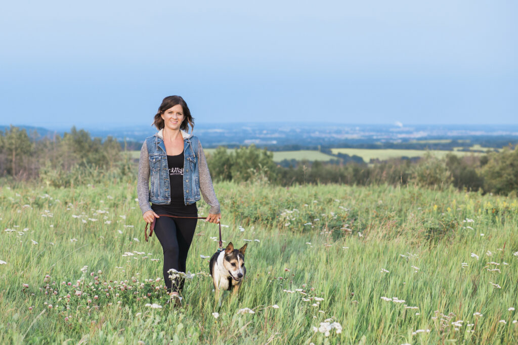 Vanessa Charbonneau walking with dog in a green field